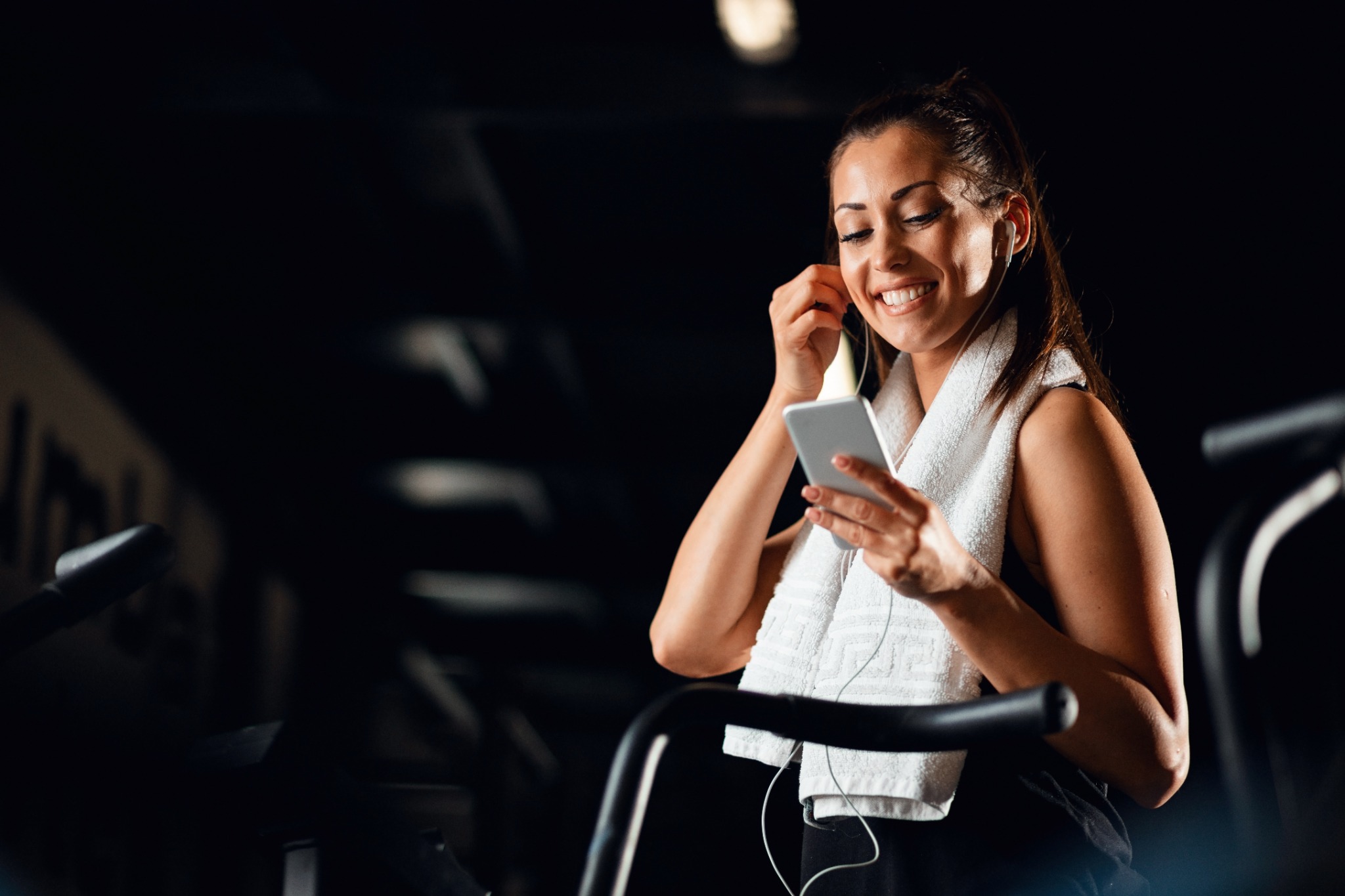 Mulher usando o celular durante treino cardiovascular