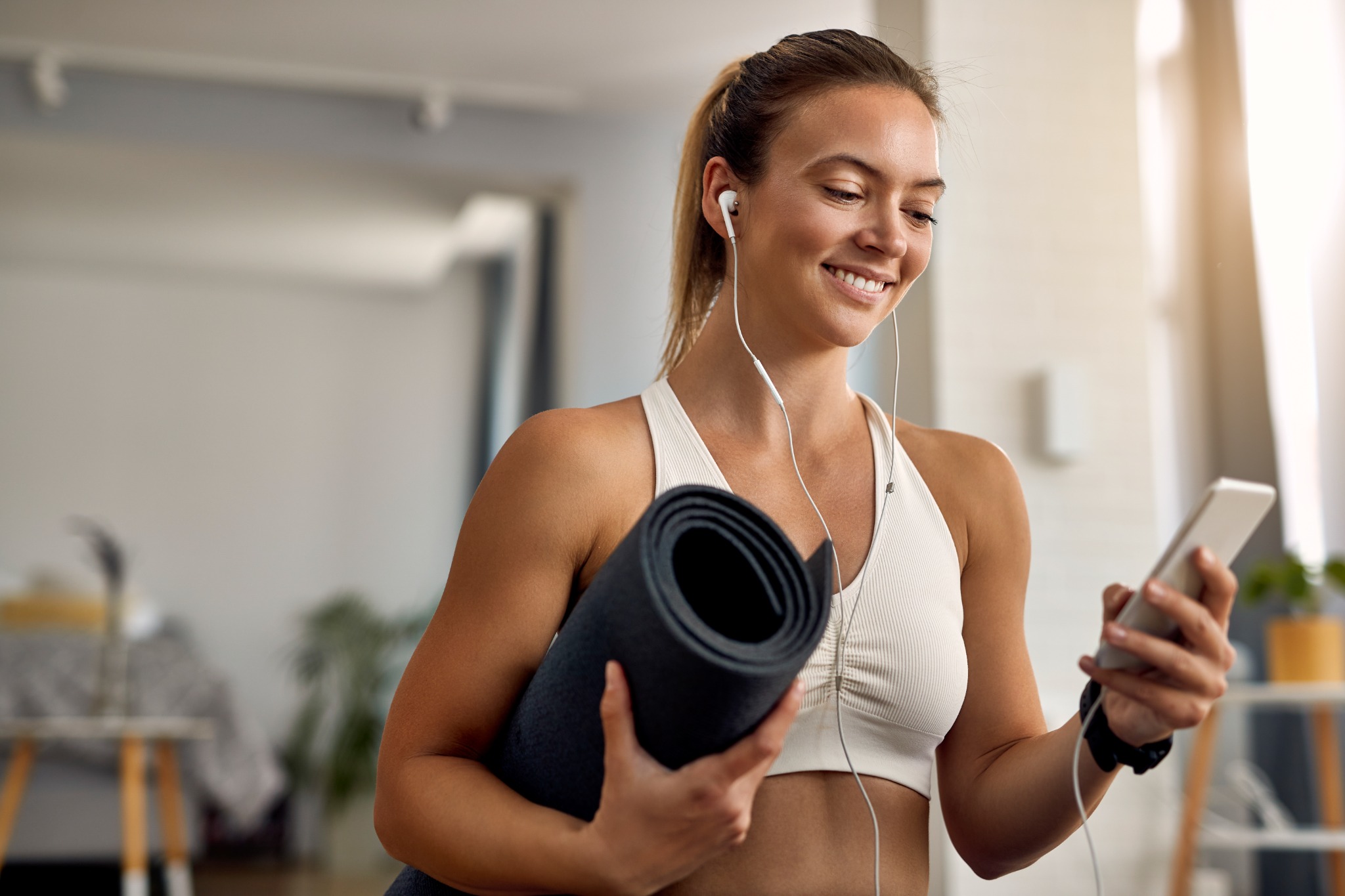 Mulher com tapete de exercícios usando o celular